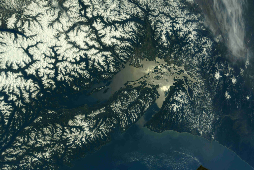 Mount Rainier's snow-capped peak and surrounding forested landscape as seen from the International Space Station on a clear day.